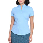 Woman wearing a light blue polo shirt and navy patterned skirt on a white background